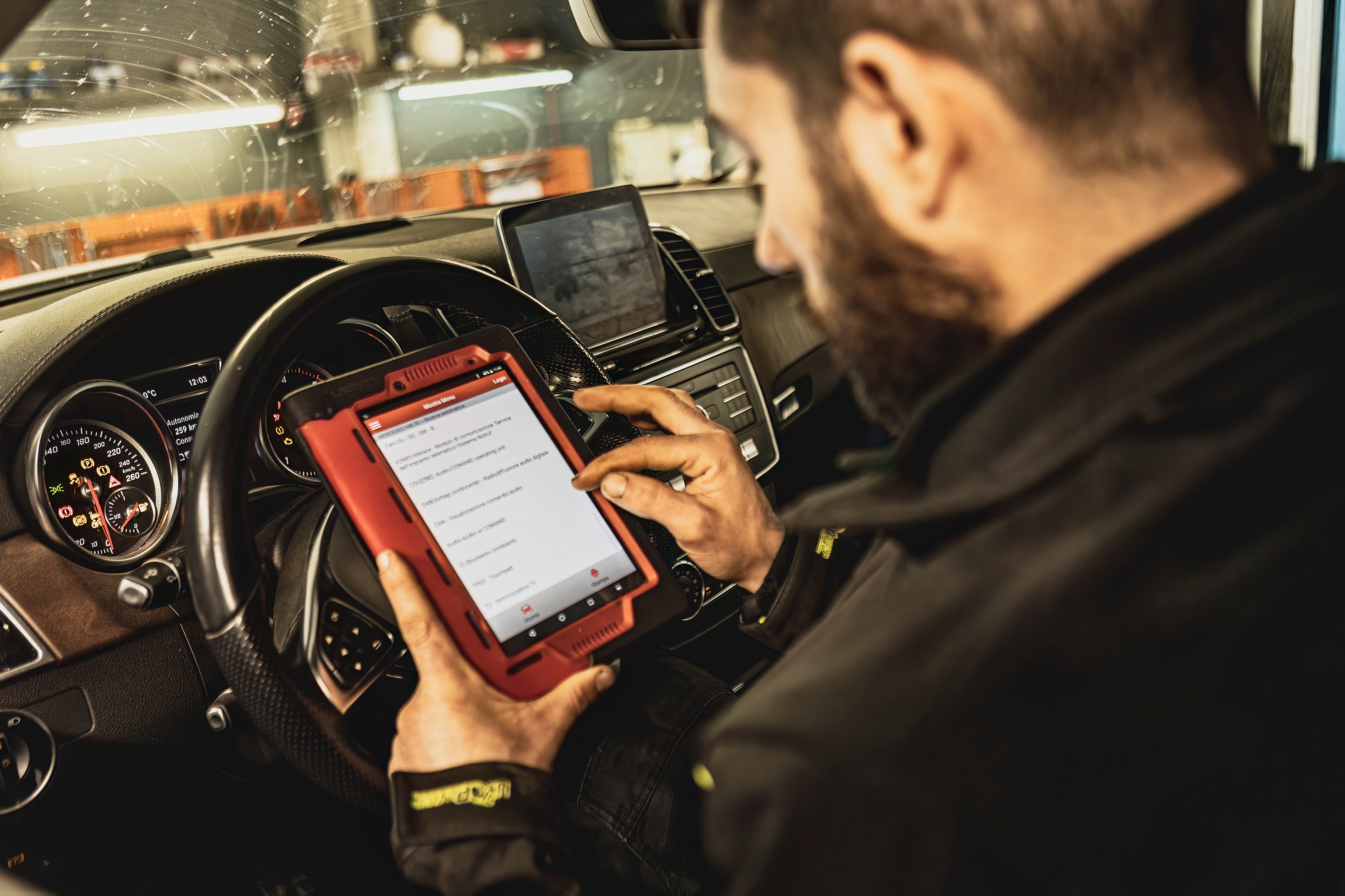 KFZ Mechatroniker im Auto mit Auslesegerät